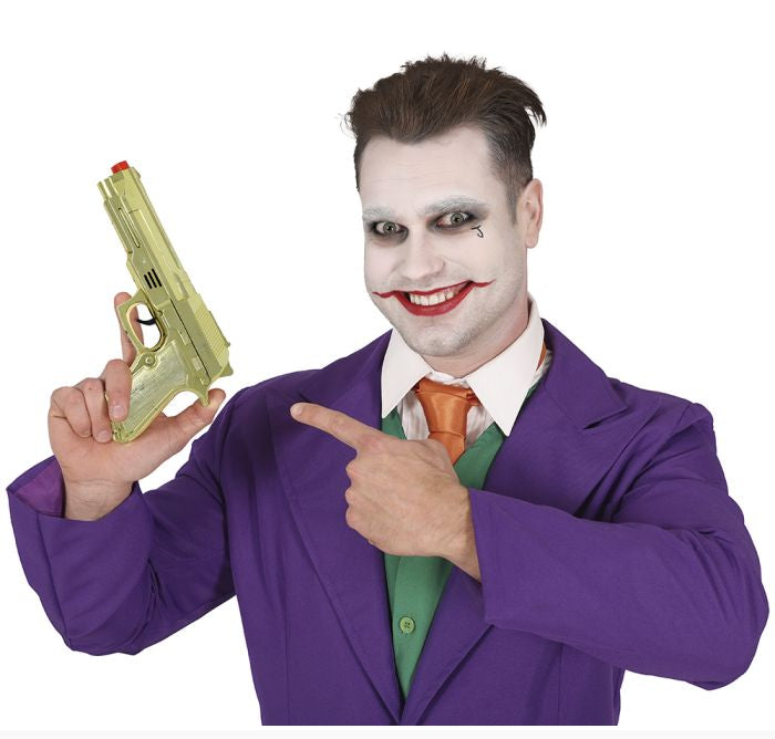 Person in a purple suit with clown makeup holding a toy gun on a white background