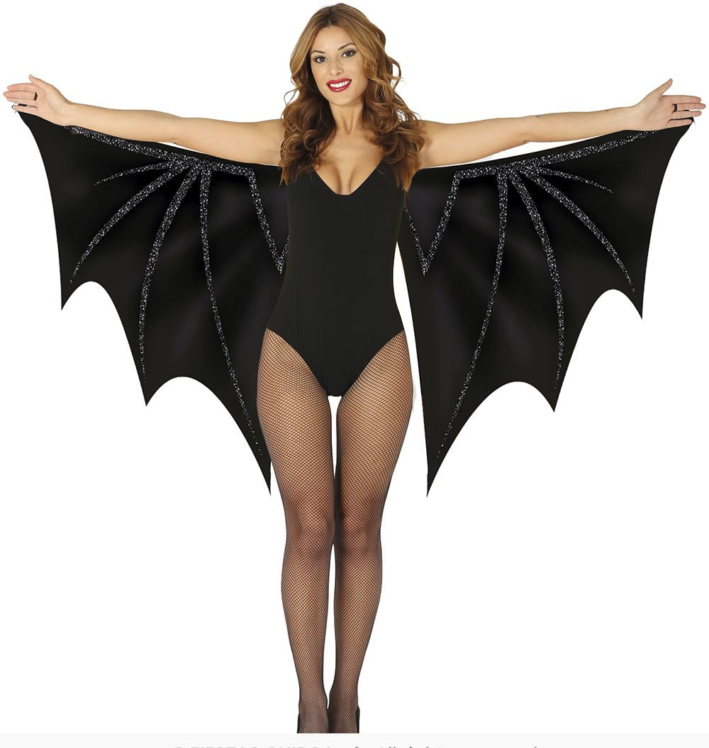 Person wearing a black bat costume with wings on a white background