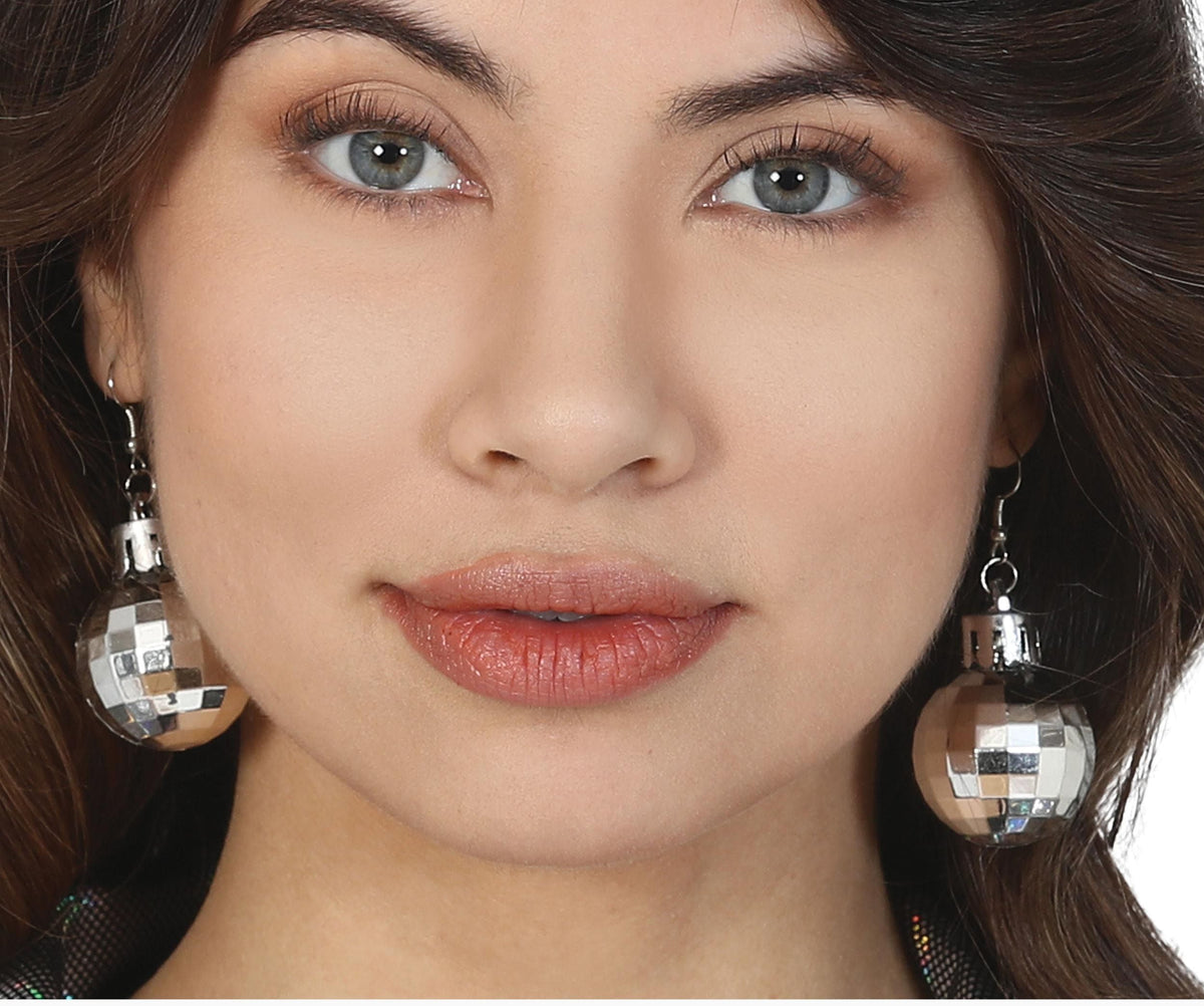 Close-up of a woman wearing silver disco ball earrings with a blurred background