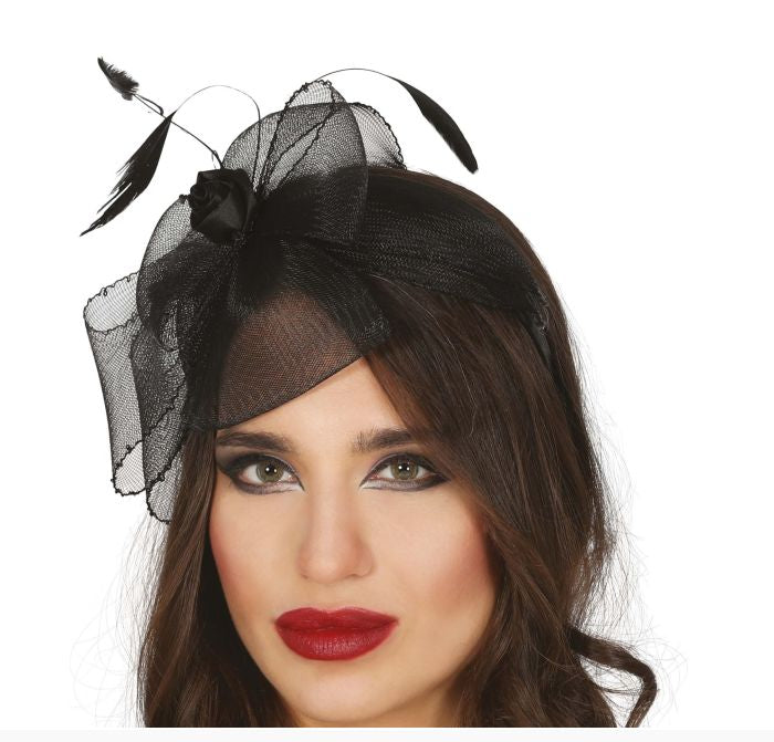 A woman wearing a black fascinator headpiece with sheer mesh, feathers, and a black rose, shown against a plain white background.
