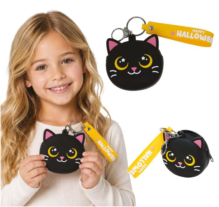 A young girl smiling while holding a small black cat-face coin purse keychain with a yellow 'Happy Halloween' strap. Two additional views of the same product are shown on the right against a white background, with a copyright notice for Fiestas Guirca s.