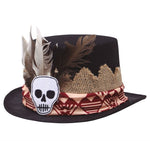 A black felt top hat decorated with brown and white feathers, a beige burlap trim, a red and beige patterned band, and a white skull patch on the front.