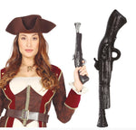 A woman wearing a pirate costume holds a toy pistol, with a larger matching toy pistol shown beside her on a white background. The costume includes a brown hat, red and white jacket with gold trim, and a brown belt.