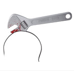 A novelty wrench-shaped headband. The headband is made of black metal wire, while the wrench head is a silver-colored forged steel plate decorated with red splatters resembling blood, featuring a small checkered pattern and the embossed text 'FORGED STEEL'.