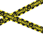 Yellow and black hazard-style caution tape printed with the words 'ZOMBIES! DANGER' and biohazard symbols, shown crossing on a white background.