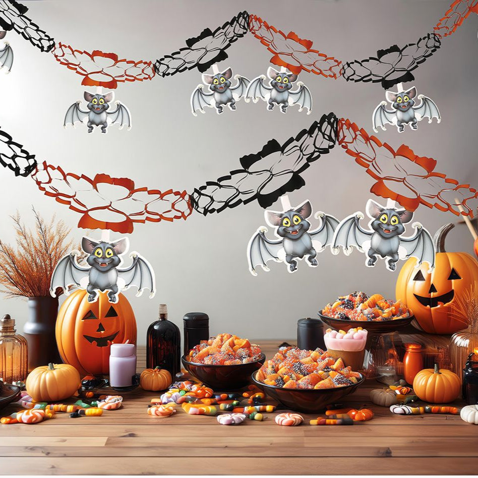 Halloween-themed table setting with pumpkins, bats, and decorative garlands on a gray wall.
