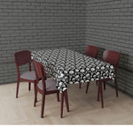 A rectangular dining table covered with a black and white skull-patterned tablecloth