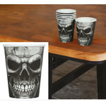 Black and white skull printed paper cups displayed on a wooden table, with a stack of cups and a single cup shown alongside a large close-up inset of the skull design.