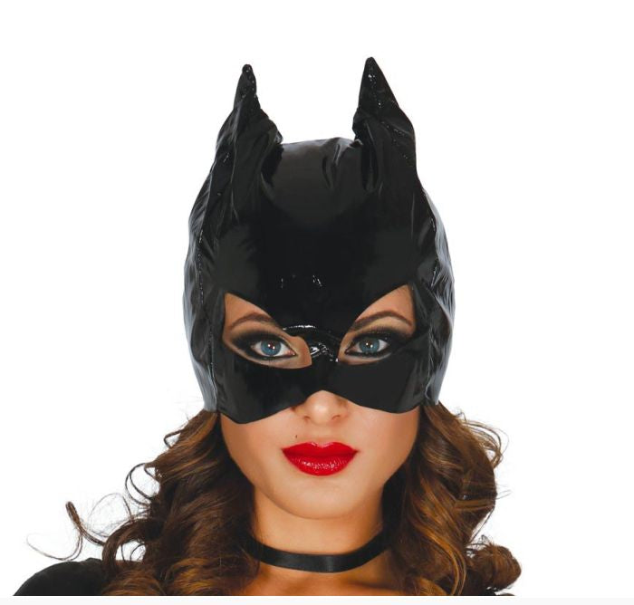 A woman wearing a glossy black Batman-style mask and pointed ear hood, shown from the shoulders up against a plain white background. 