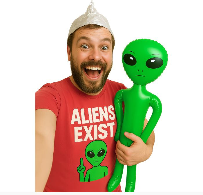 Man wearing a red shirt with an alien graphic and text, holding a green inflatable alien toy.