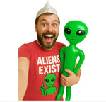Man wearing a red shirt with an alien graphic and text, holding a green inflatable alien toy.