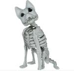 A small gray plastic skeleton dog figurine sitting down, shown against a plain white background with a copyright watermark at the bottom.