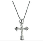 A silver-toned cross pendant necklace with ornate engraved details, hanging from a matching box chain against a plain white background.