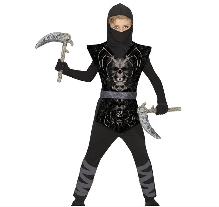 A child modeling a black ninja costume with a skull graphic on the chest, holding toy scimitar and scythe props against a white background.