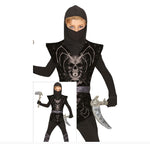 A child wearing a black ninja costume with a hooded mask, sleeveless top, printed skull design, and silver toy weapons, shown on a white background with a smaller inset of the full outfit.
