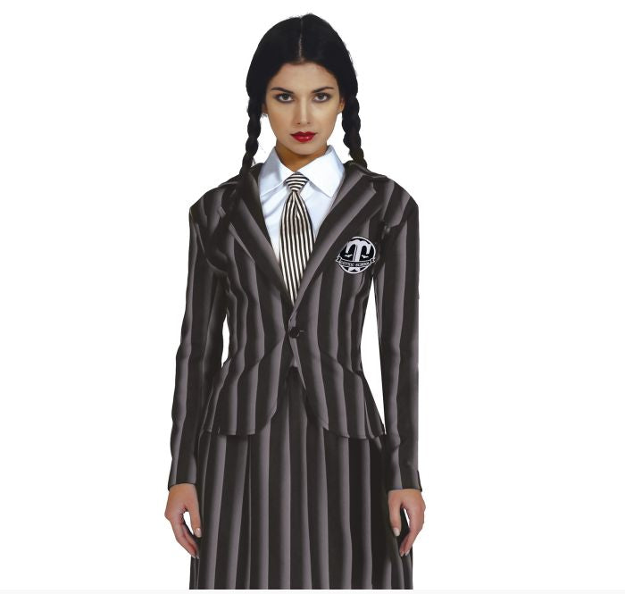 A woman modeling a Wednesday Addams-style costume consisting of a dark gray and black pinstriped blazer with a white shirt, striped tie, and a matching skirt. A circular skull-and-crossbones patch is pinned to the blazer.